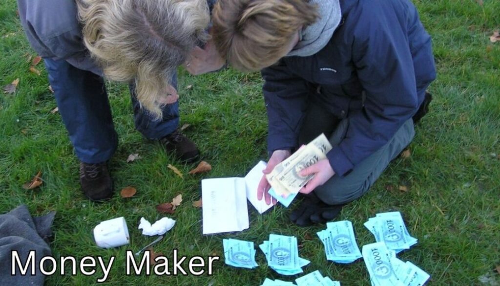 Billedet viser to personer, der sidder på græsset og tæller seddelbunker i spilpenge – en del af teambuildingaktiviteten Money Maker. Aktiviteten handler om strategi, samarbejde og økonomisk tænkning, hvor deltagerne konkurrerer om at tjene mest muligt "penge" gennem opgaver og forhandlinger. En sjov og engagerende måde at styrke kommunikation og beslutningstagning i teamet.
