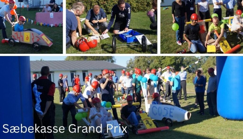 Billedet viser den sjove teambuildingaktivitet Sæbekasse Grand Prix, hvor deltagerne i hold bygger og dekorerer deres egne sæbekassebiler. Iført hjelme og godt humør dyster de i kreativitet, samarbejde og fart – alt sammen i en festlig og farverig stemning udendørs.
